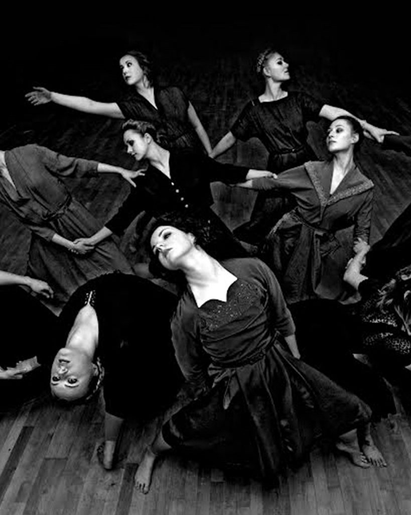 Ausschnitt einer Tanzszene mit neun Tänzerinnen, dunkler Hintergrund, schwarz-weiß.