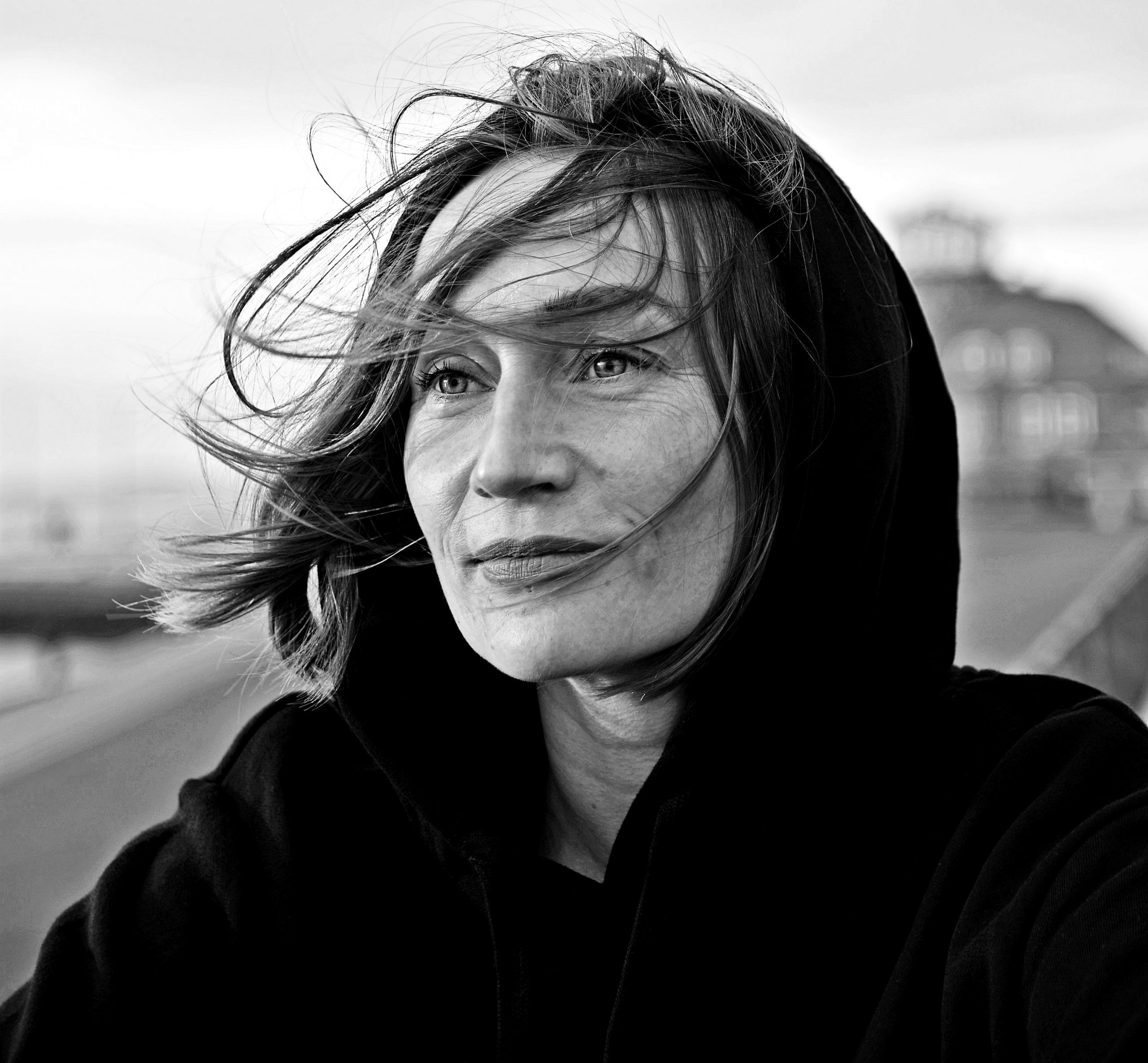 Portrait von Sarah Haack, Haare wehen im Wind, Kapuze auf.